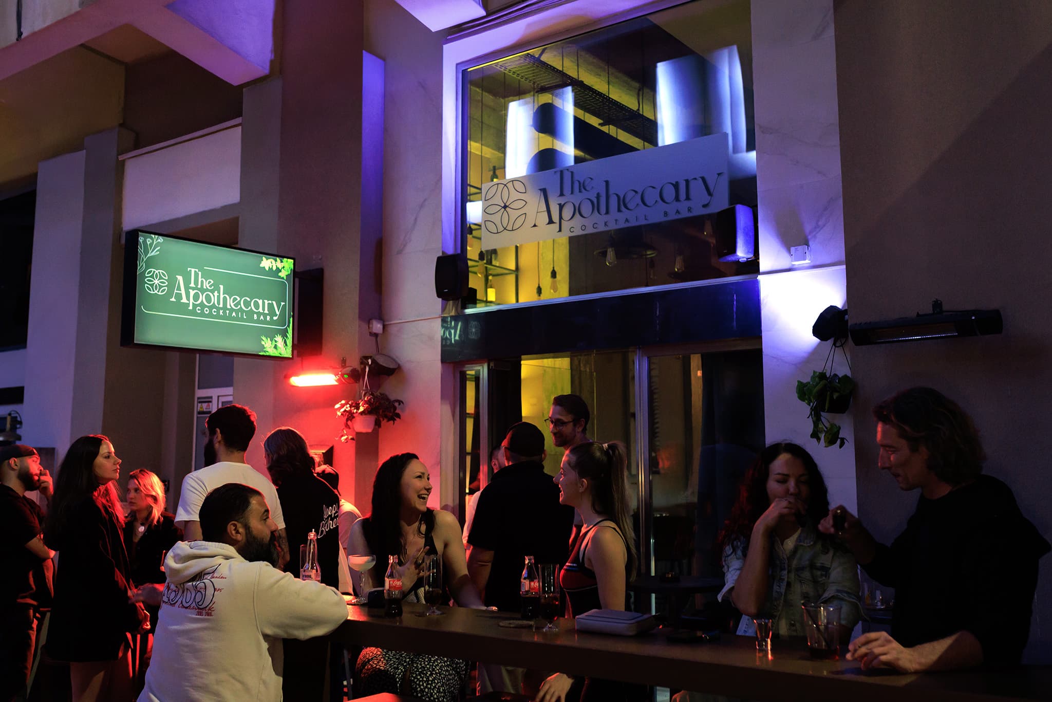 Bartender pouring a bright yellow cocktail behind the bar