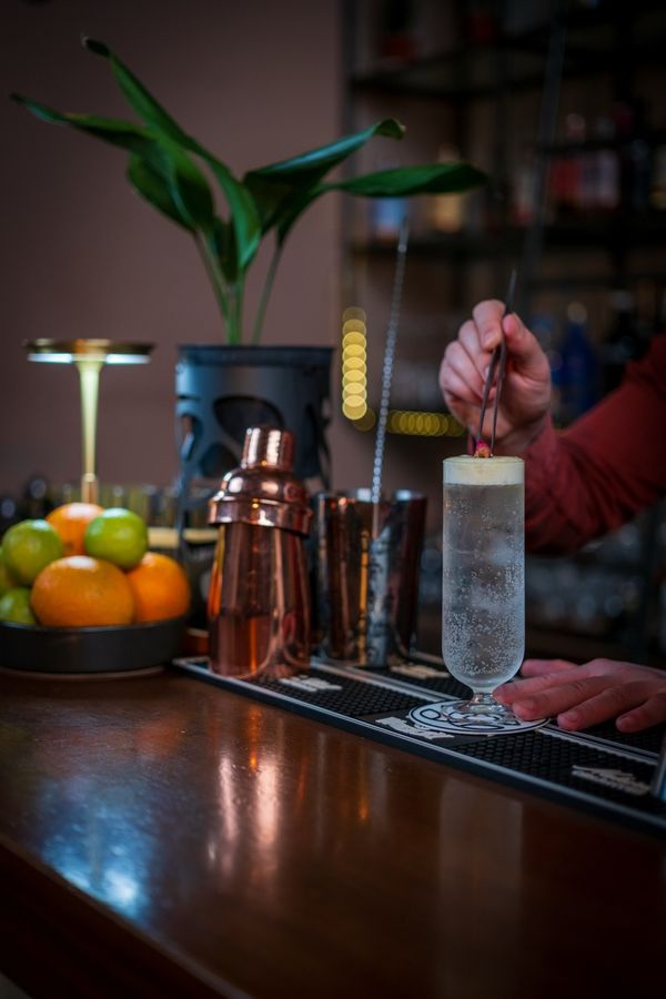 Bartender garnishing a tall sparkling cocktail at the bar