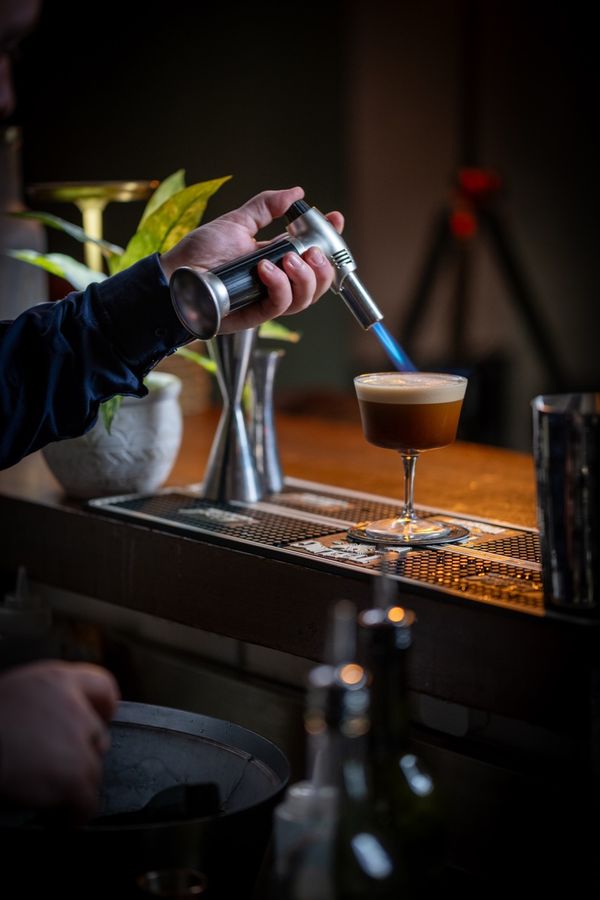 Bartender torching the top of a cocktail